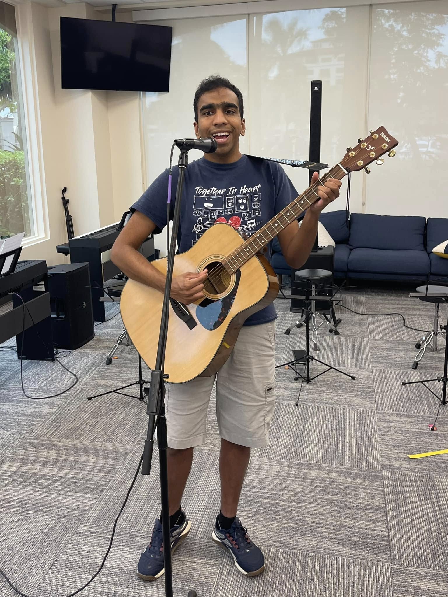 Hari performing with guitar at the microphone